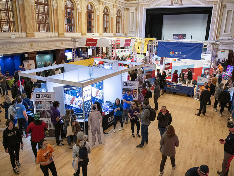 Visitors exploring STEM South West exhibition stands inside a large hall with science and technology displays.